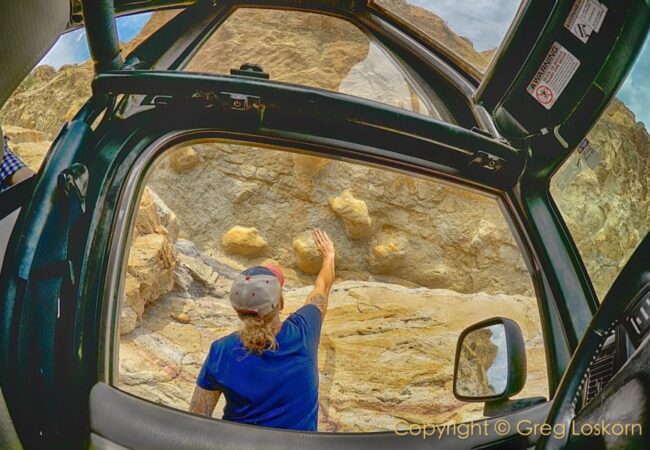 Woman outside of jeep touching Red Canyon rocks