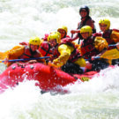 family and guide navigating waves on whitewater rafting tour