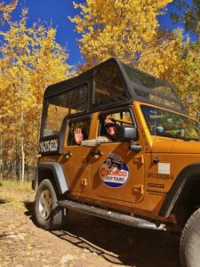 Colorado Jeep Tours guide waving from jeep with yellow leaves in background
