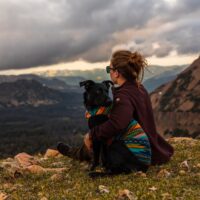 woman sitting with dog during hike