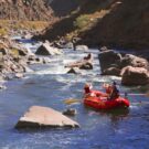 two guests and guide through calm waters on rafting tour